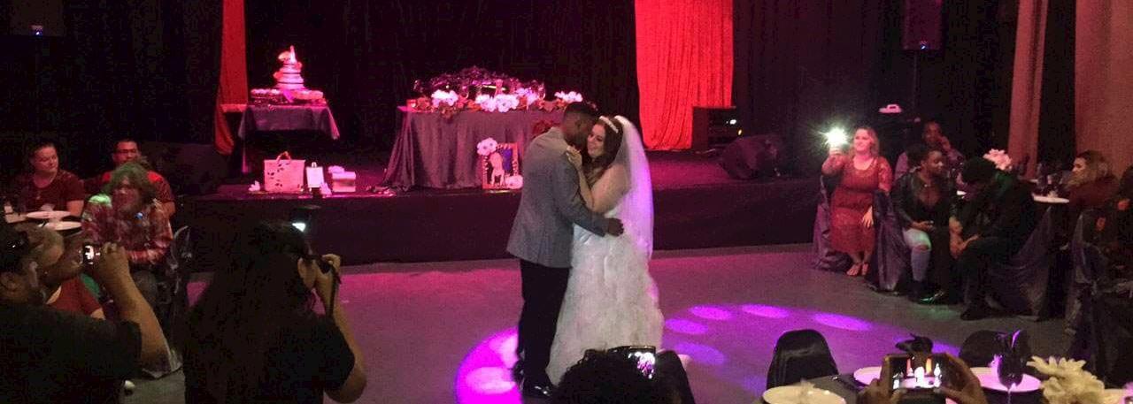 A wedding reception with a bride and groom dancing in the center of the room.