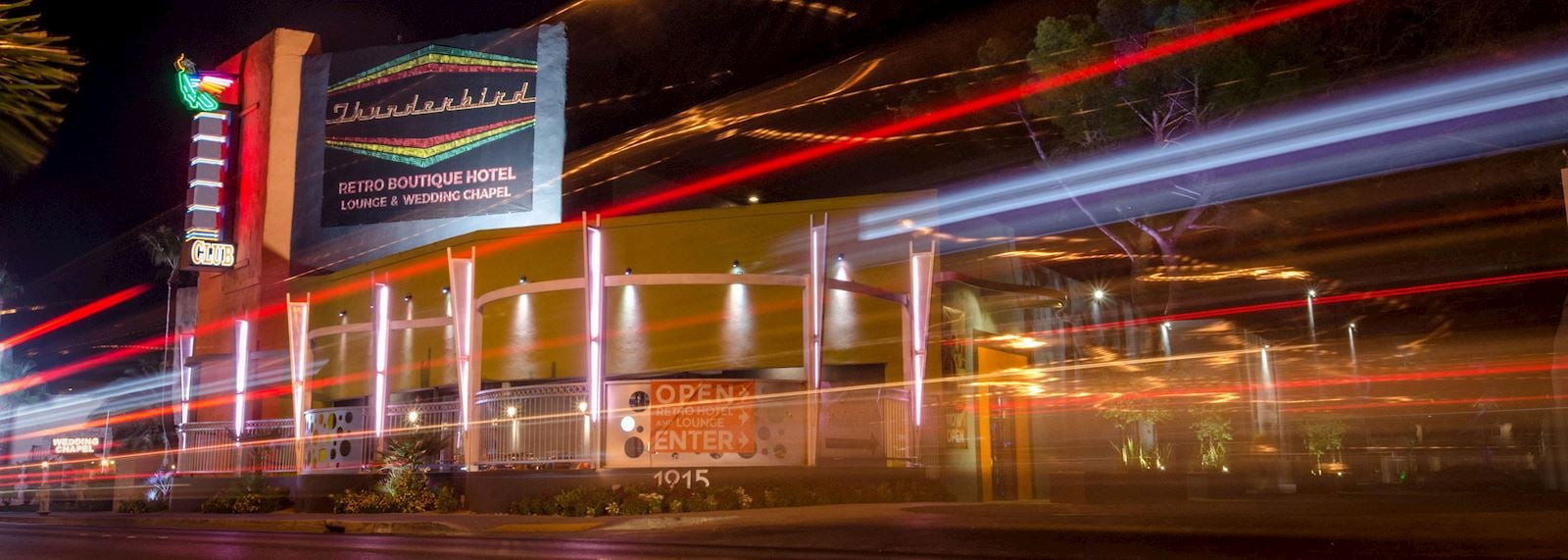 A nighttime view of a building with a neon sign reading 'Thunderbird' and 'Retro Boutique Hotel'.