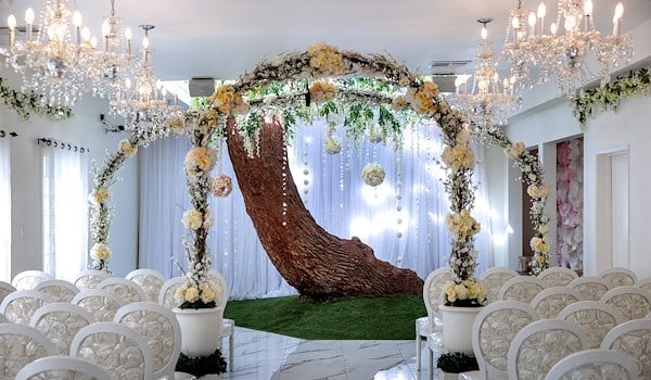 a wedding ceremony setup with a floral archway and white chairs