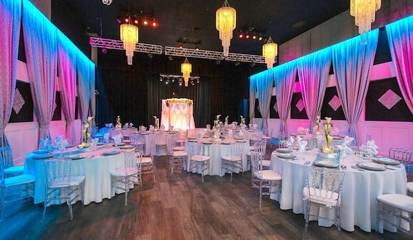 A large, elegantly decorated meeting room with tables, chairs, and colorful lighting.